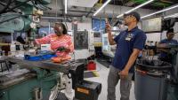 A participant at a Georgia Tech manufacturing workshop cuts metal on industrial equipment. 
