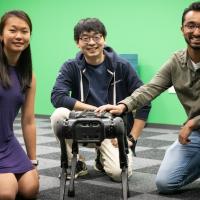 Three students kneeling around a spot robot