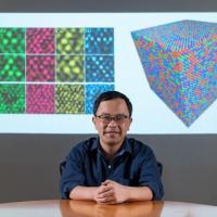 <p>Ting Zhu, professor of mechanical engineering at Georgia Tech, in front of his TEM images of polycrystalline metals and a graphic simulating atomic structure</p>