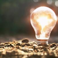 An Adobe stock conceptual image of a lighted bulb in the dirt illustrating new technology that draws energy from dirt.