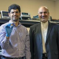 <p>ECE professor Ali Adibi with Ph.D. candidate Sajjad Abdollahramezani holding their packaged tunable metasurface device.</p>
