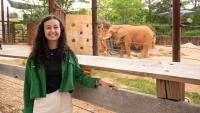 Arianna Mastali stands in front of an African elephant in the background at Zoo Atlanta.