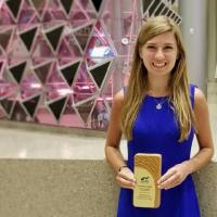 <p>Grace Brosofsky, BSEnvE 2017, stands with her Student Sustainability Leadership award from the Association for the Advancement of Sustainability in Higher Education. She won the award for a project she created with Engineers for a Sustainable World at Georgia Tech researching natural weed-control options. (Photo Courtesy: Grace Brosofsky)</p>