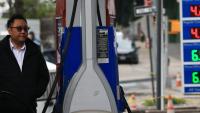 A person filling gas in his car with the gas prices shown in the foreground