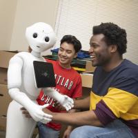 Two students interact with humanoid robot. 