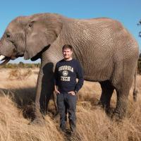 Georgia Tech mechanical engineering Ph.D. student, Andrew Schulz, standing in front of an elephant.