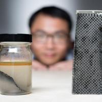 <p>Kai Yu, a former postdoctoral researcher in The George W. Woodruff School of Mechanical Engineering at Georgia Tec, sits behind a piece of carbon fiber composite immersed in alcohol. (Credit: Rob Felt, Georgia Tech)</p>
