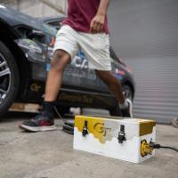 A gold and white charger box in front of a car