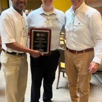 Three men holding an award