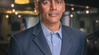 Karthik Ramachandran smiles in a navy suit coat