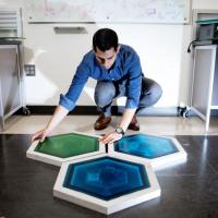 <p>Ilan Stern, a GTRI senior research scientist, shows piezoelectric tiles that will be used to create a lighted outdoor footpath at the NASA Kennedy Space Center’s Visitor Complex at Cape Canaveral, Florida. He’s holding the electronic components used in the tiles. (Credit: Branden Camp, Georgia Tech)</p>