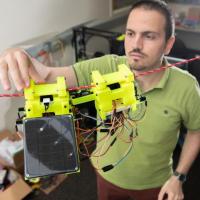<p>Graduate Research Assistant Gennaro Notomista shows the components of SlothBot on a cable in a Georgia Tech lab. The robot is designed to be slow and energy efficient for applications such as environmental monitoring. (Photo: Allison Carter, Georgia Tech)</p>
