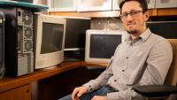 Zsolt Kira sitting in office chair surrounded by old computers